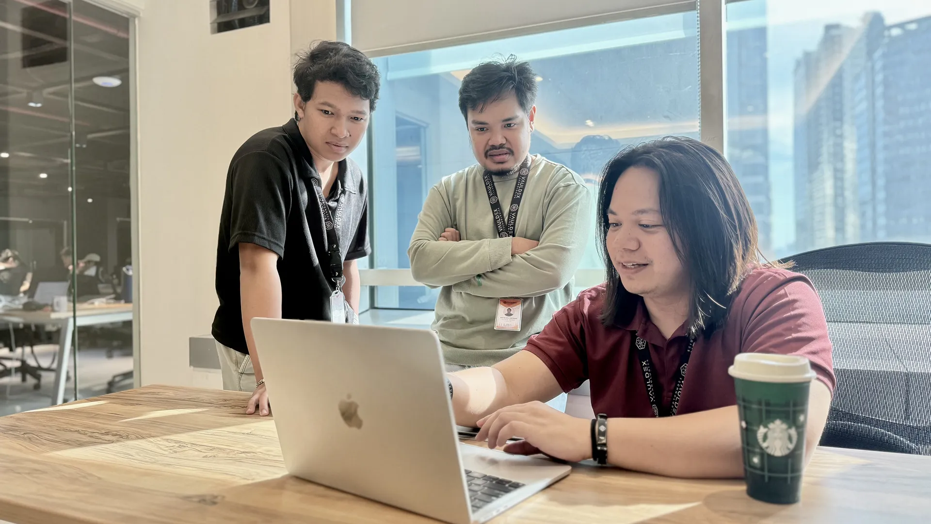 Kynji and his colleague are looking at Kynji's laptop